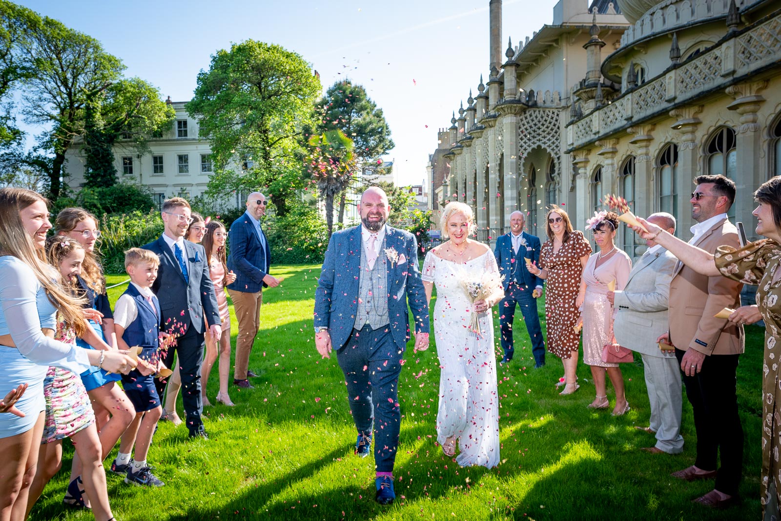 Georgina and Andy walk through confetti after outside Brighton Royal Pavilion after their wedding. 
