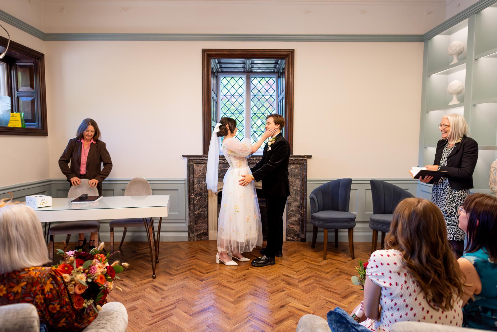 Lola and Laurance look at each other at the top of the aisle in the Ainsworth Room at Lewes Registry Office after their wedding.