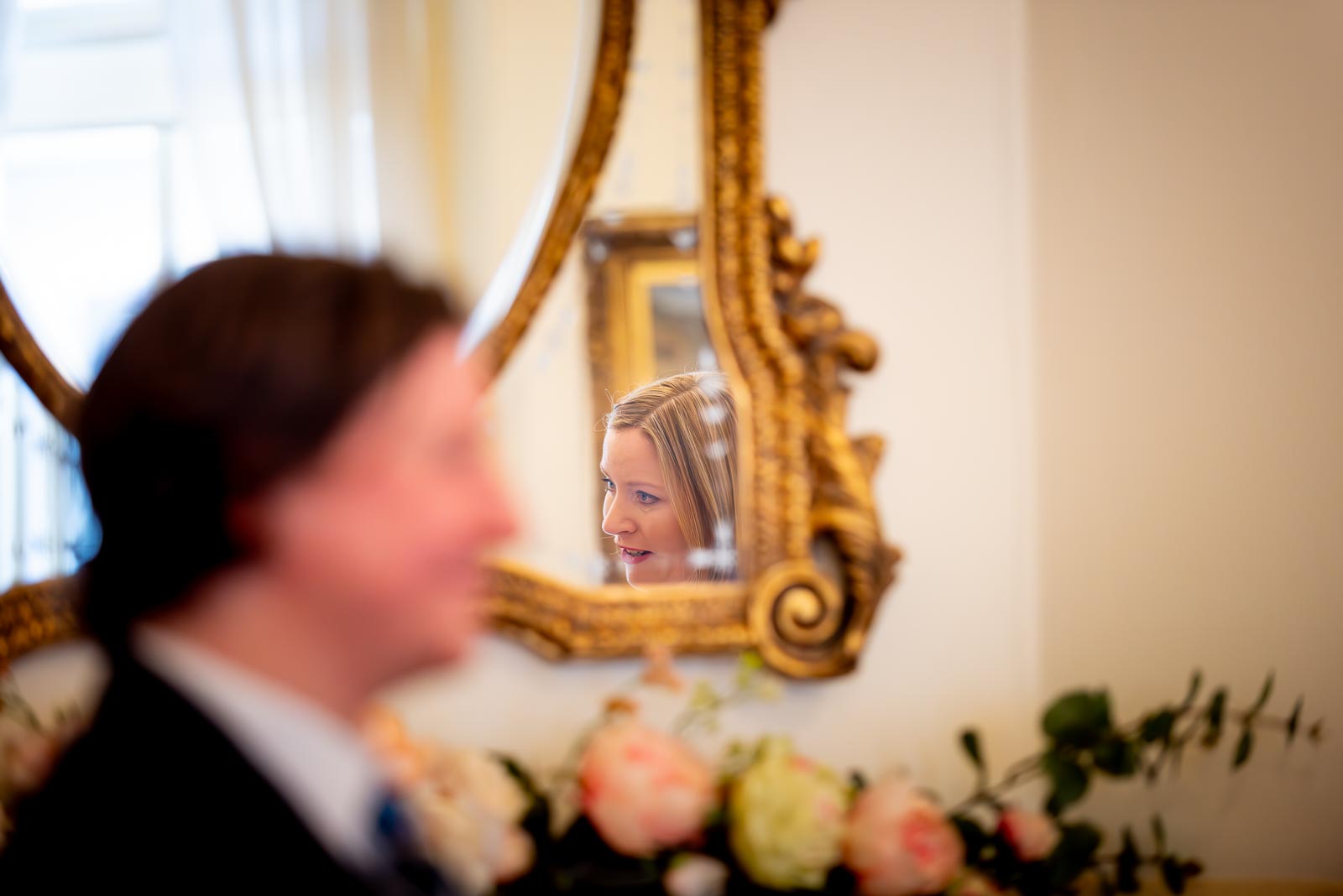 Clare is reflected in the mirror whilst reading a handwritten note to Sam during their Civil Partnership in the Regency Room at Brighton Town Hall. 