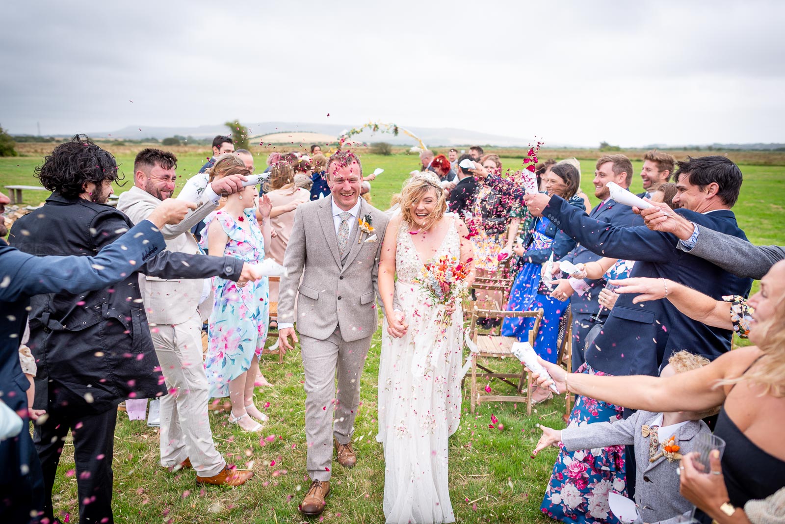 Eleanor and Marc walk through confetti thrown by guests after their wedding at the Party Field near Lewes.