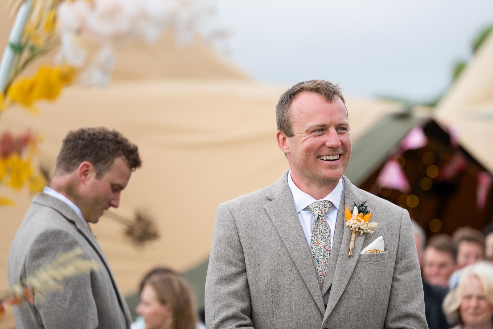 Marc waits patiently for his bride to be Eleanor to arrive at the Party Field near Lewes with his best man and twin brother in the background.