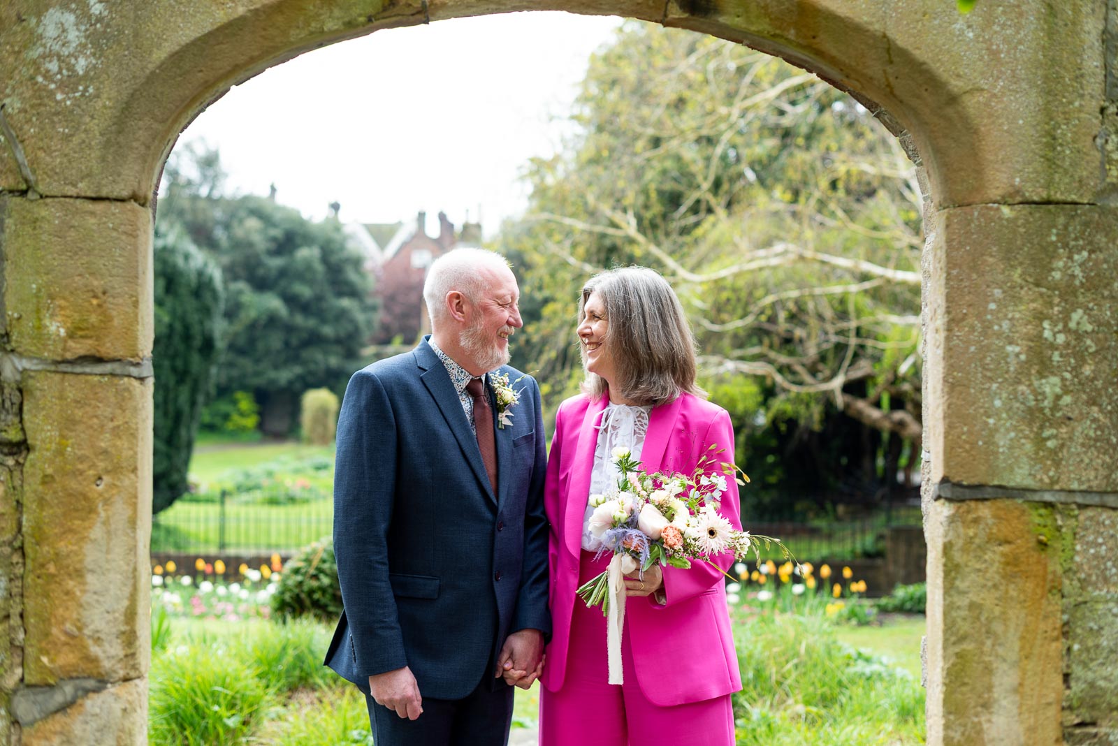 Helen and Tony smile at each other in one of the arches at Southover Grange in Lewes following their wedding