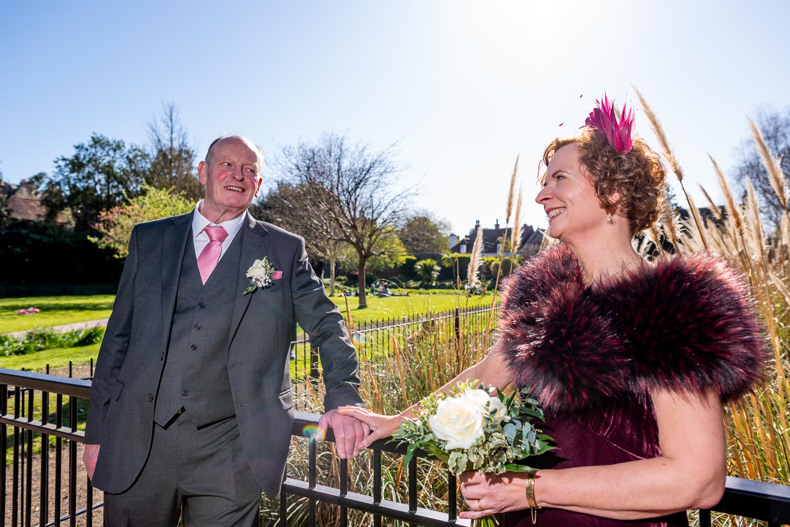 Jill and John smile at each other on one of the bridges over the Winterbourne in Southover Grange following their Wedding