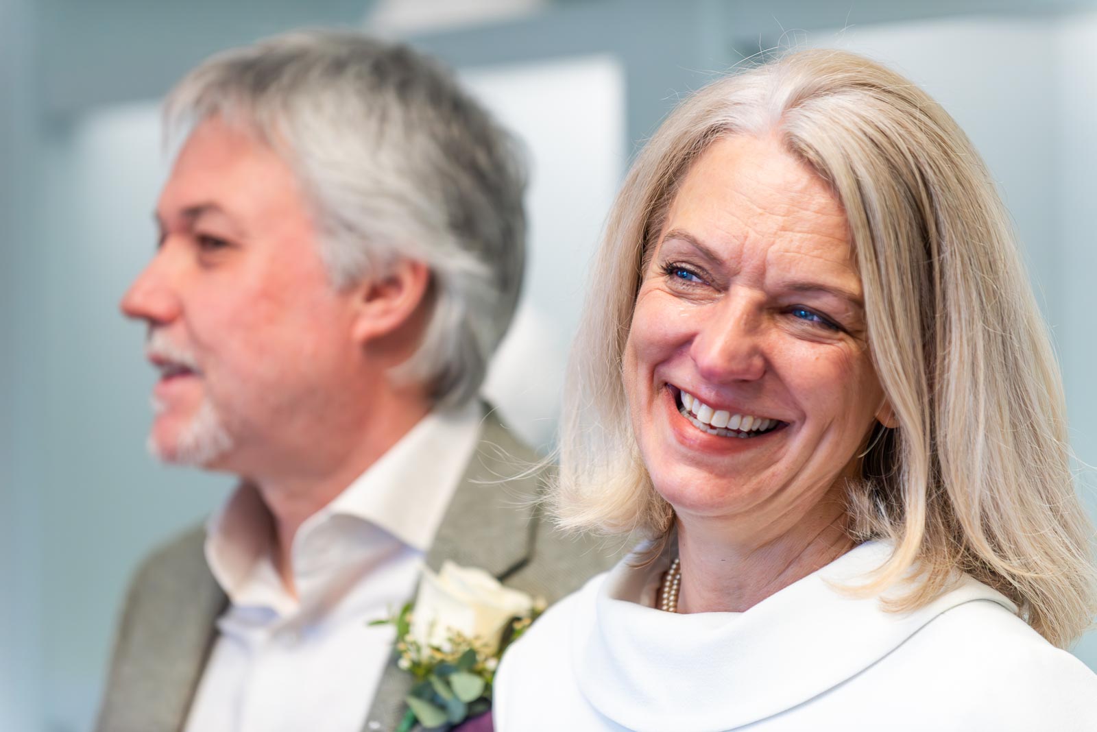 Jo smiles with Darren in the background during their wedding in Lewes Registry Office