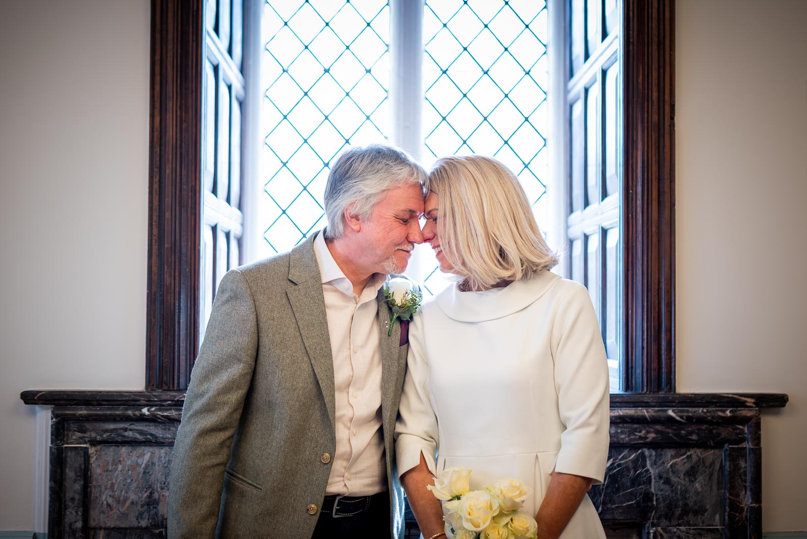 Jo and Darren enjoy a moment on front of the lead set window in the Evelyn Room at Lewes Registry Office