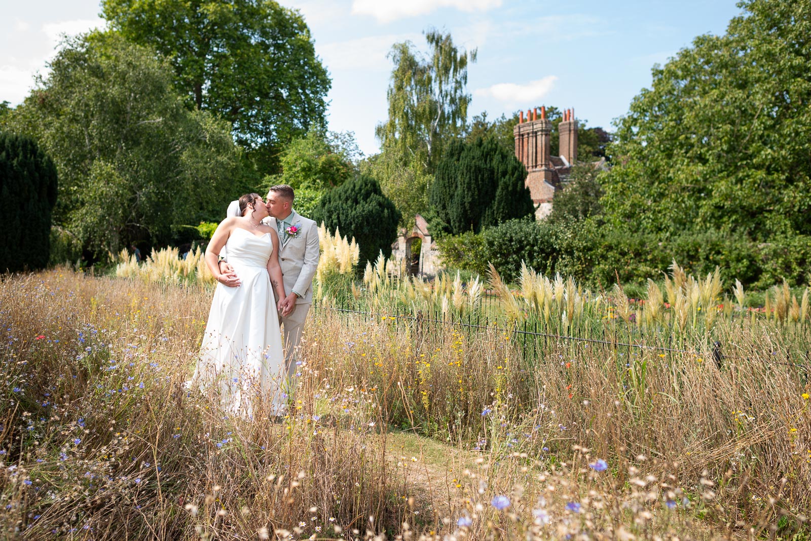 Tamsyn and Karl kiss among the wild flowers at Southover Grange following their wedding at Lewes Registry Office.