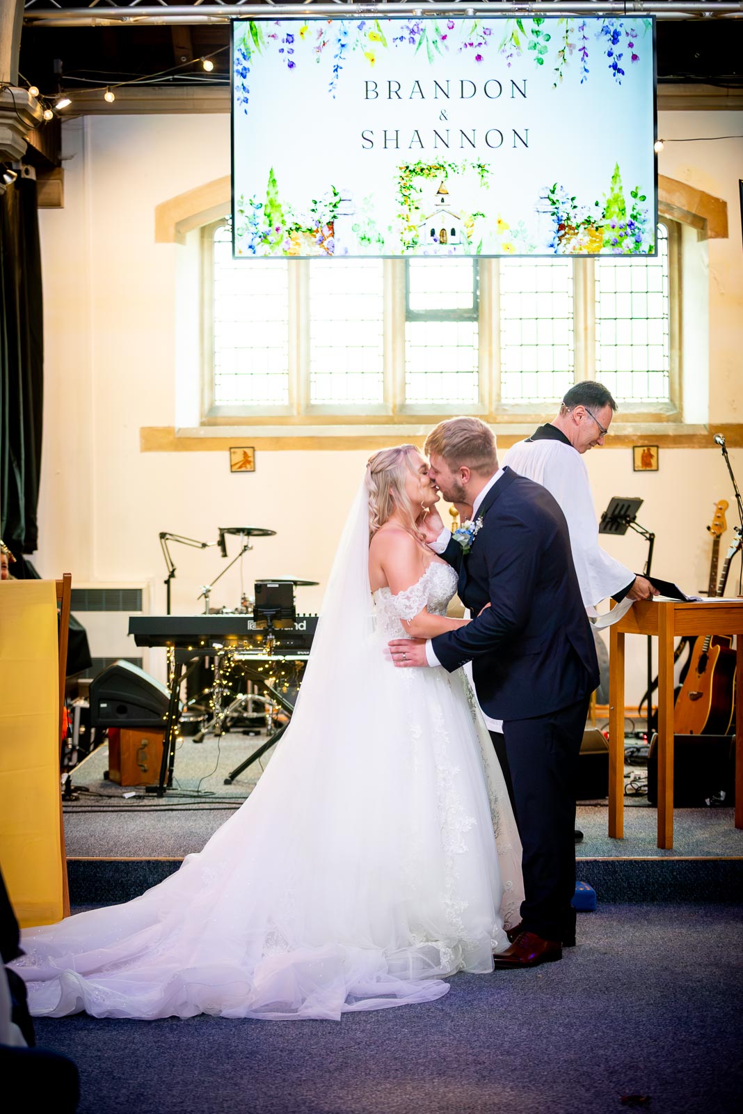 Shannon and Brandon kiss at the bottom of the aisle in St. Michael and All Angels Church in Eastbourne during their wedding.