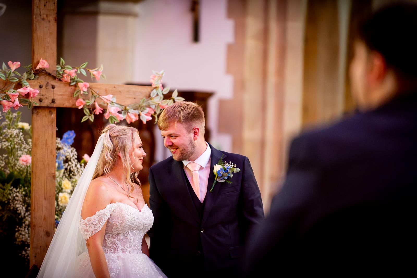 Shannon and Brandon smile at eachother at the bottom of the aisle in St. Michael and All Angels Church in Eastbourne during their wedding.