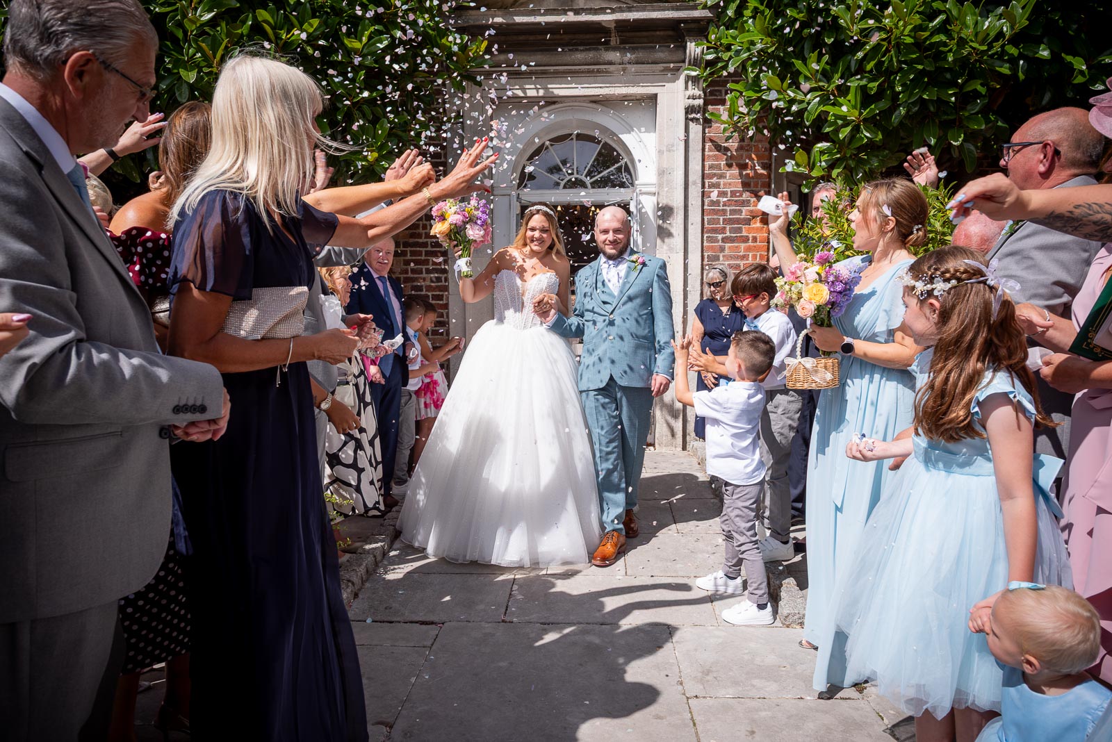 Sarah and Lewis walk through confetti thrown by guests after their wedding in the gardens at Pelham House Hotel, Lewes. 
