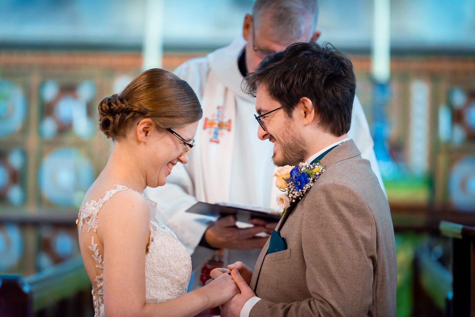 Stephanie and Lewis enjoy a funny moment whilst exchanging rings at their wedding in The Church of St Peter and St Paul in Hellingly.