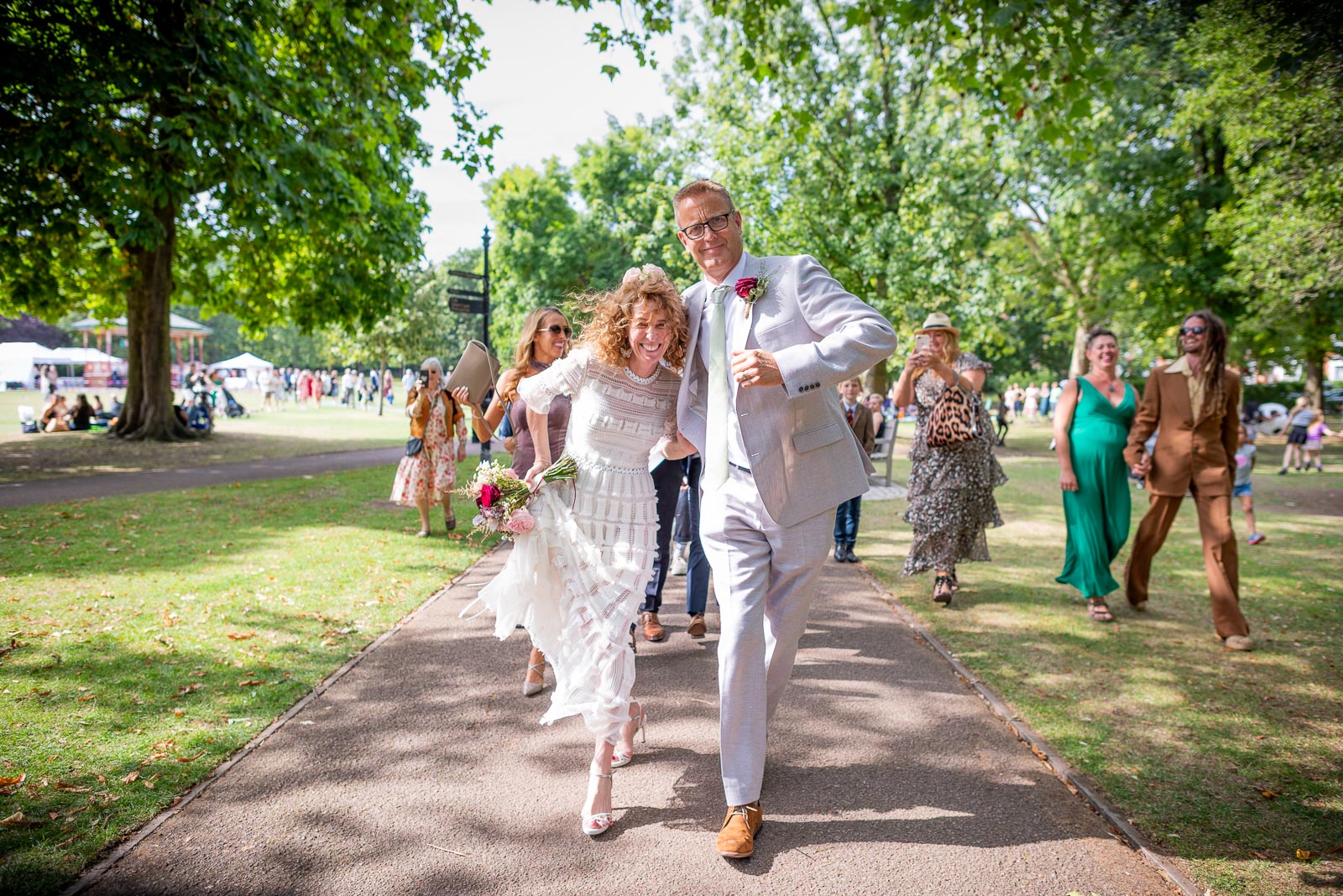 Kitty and Will dance to the wedding venue after their wedding in the Band Stand at Queens Park in London