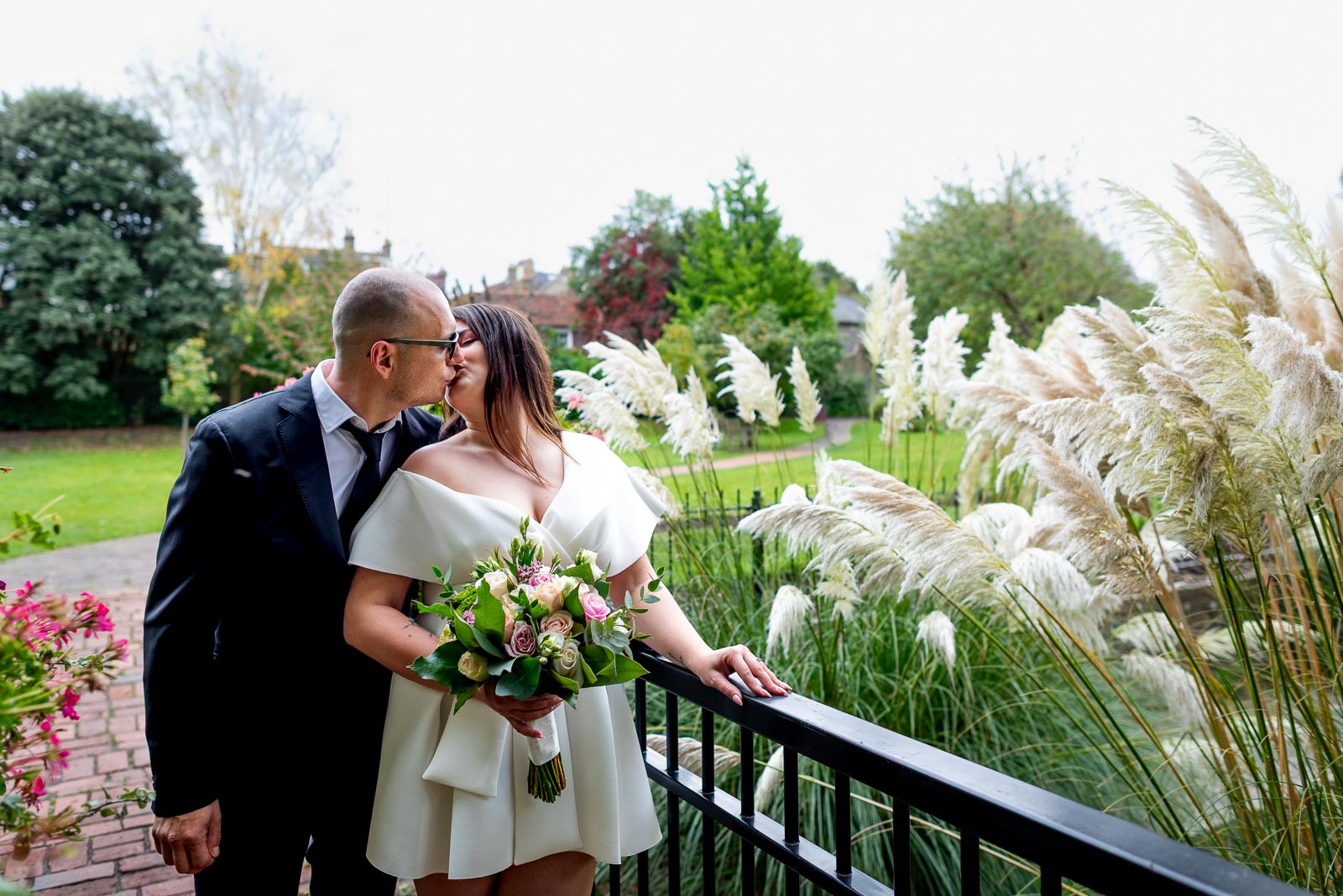 Maria and Robert embrace on a bridge in Southover Grange, Lewes after their wedding.