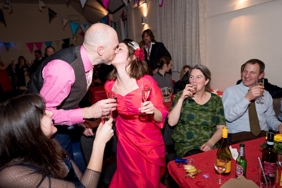 Annie and Mark kiss after toasting eachothers health at their wedding reception in Firle Village Hall.