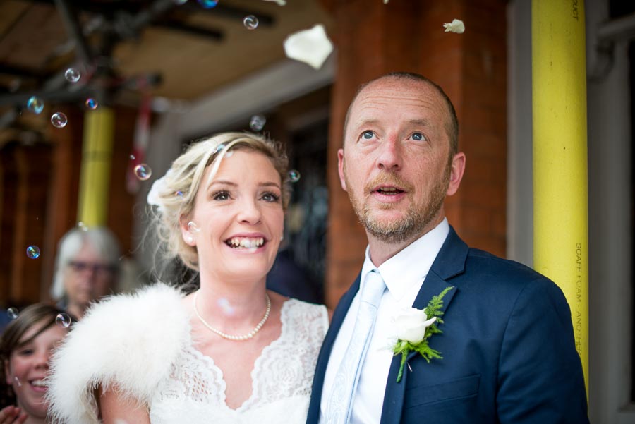 Richard and Emily look at bubble confetti blown by their wedding guests after getting married at Lewes Town Hall.